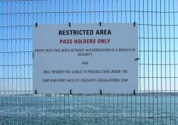 ISPS. Tabliczka zakazująca wstępu osobom nieupoważnionym zawieszona na płocie w porcie morskim Southampton. 