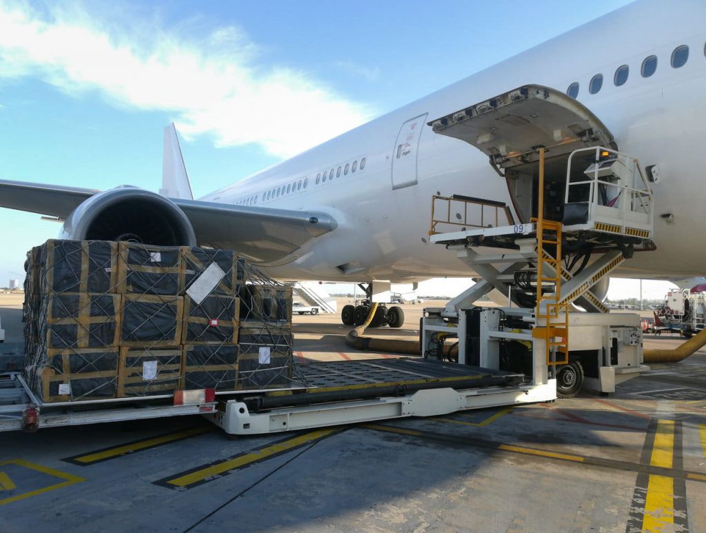 Transport otniczy pandemia. Ładunek w trakcie pakowania do luku bagażowego samolotu pasażerskiego.
